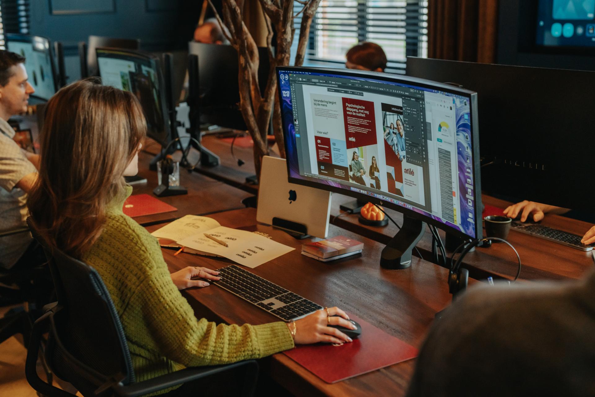 Designer werkt aan website ontwerp op groot scherm